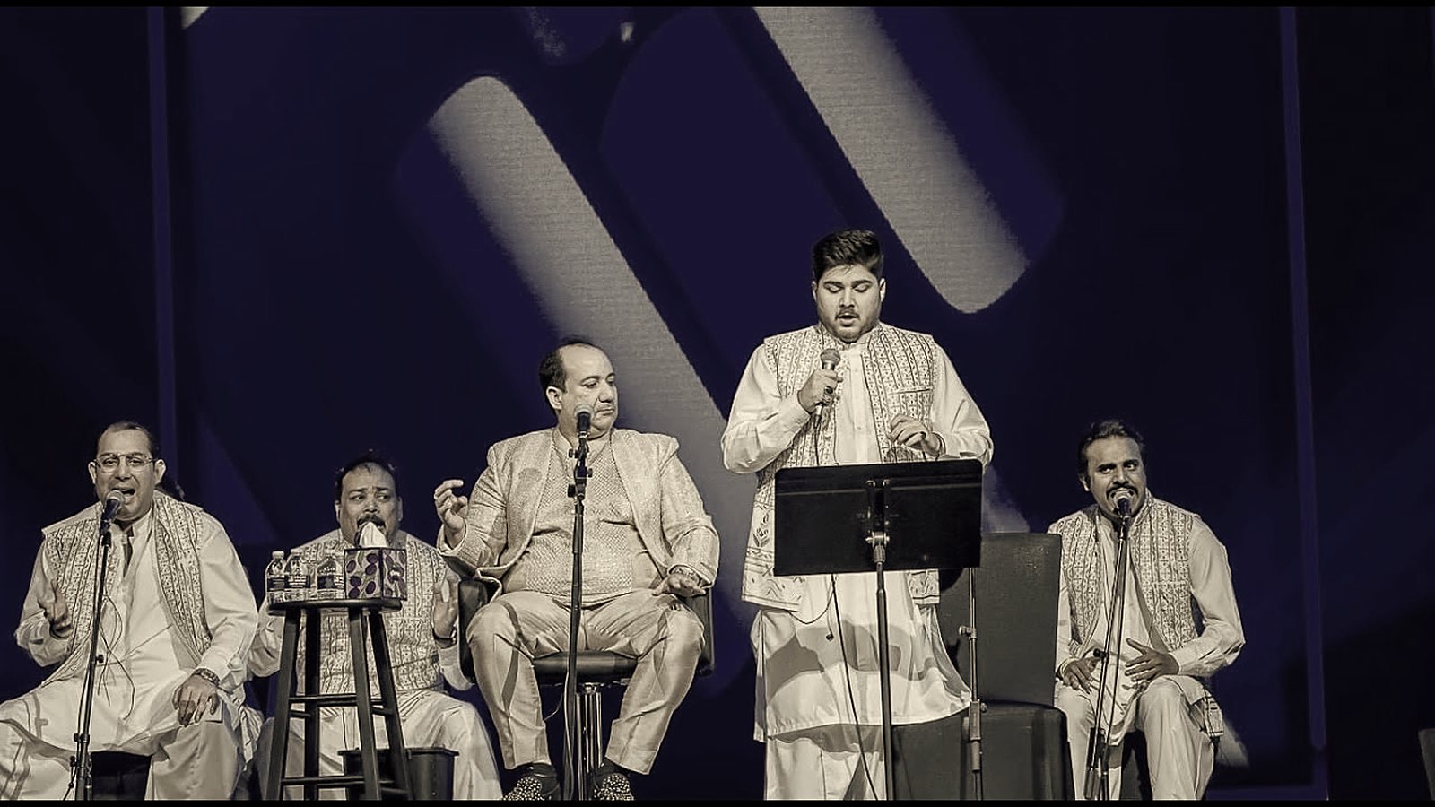 Rahat Fateh Ali Khan seated and Shahzaman Ali Khan standing, performing with their group